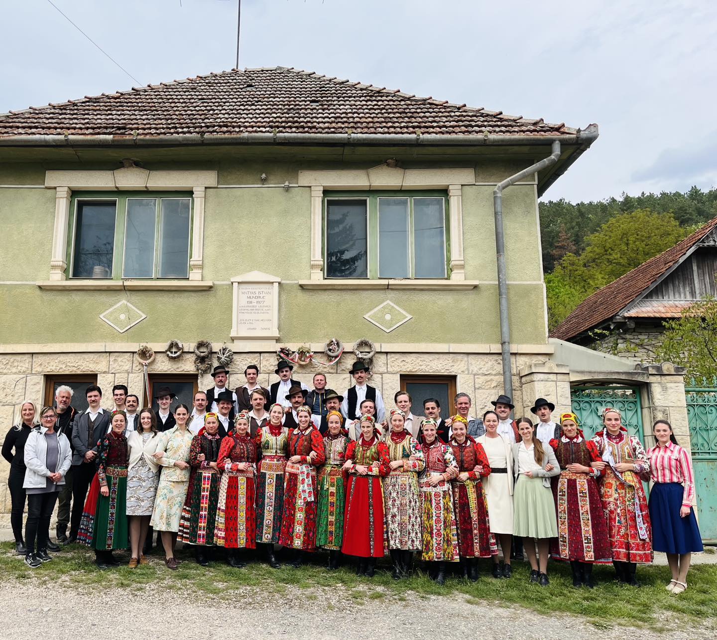 A Magyar Állami Népi Együttes Magyarvistán, a Mundruc–emlékház, – tábla előtt